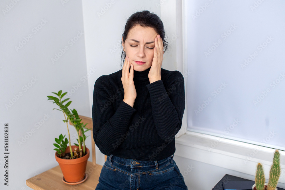 A woman experiences headache and toothache. Sitting with his eyes closed A woman experiences headache and toothache. Sitting with his eyes closed
