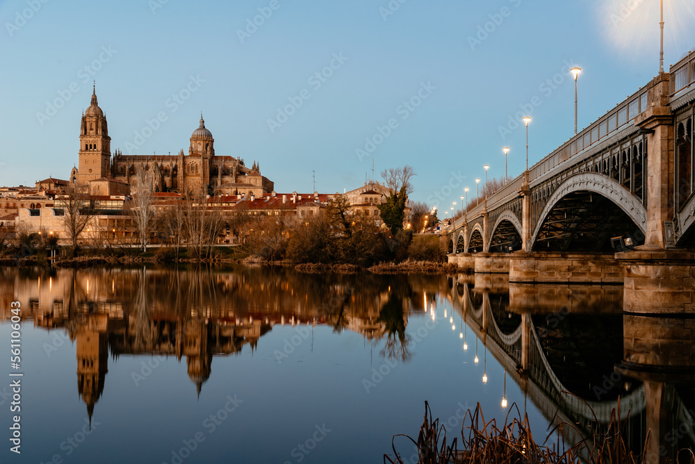 Obraz premium Scenic view of Salamanca with the Cathedral and iron bridge reflected in the Tormes River at sunset. Castilla Leon, Spain