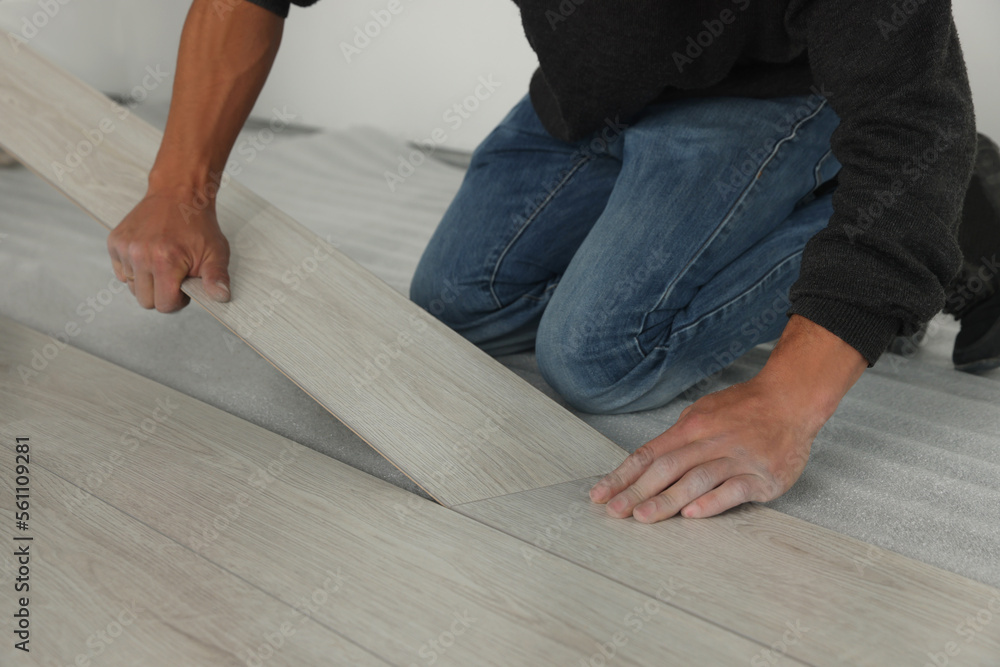 Worker installing new laminate flooring in room, closeup Worker installing new laminate flooring in room, closeup