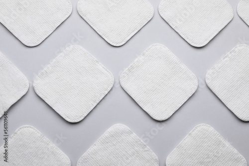Many clean cotton pads on light grey background, flat lay