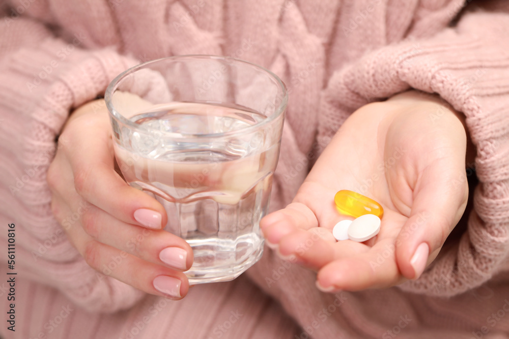 Woman with glass of water and pills, closeup view Woman with glass of water and pills, closeup view