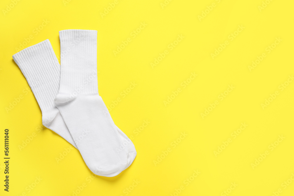 Pair of white socks on yellow background, flat lay. Space for text Pair of white socks on yellow background, flat lay. Space for text