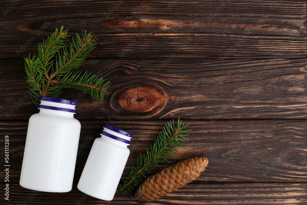 White medical bottles, spruce twigs and cone on wooden table, flat lay. Space for text
