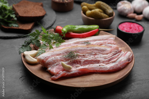 Tasty pork fatback and ingredients on black table, closeup