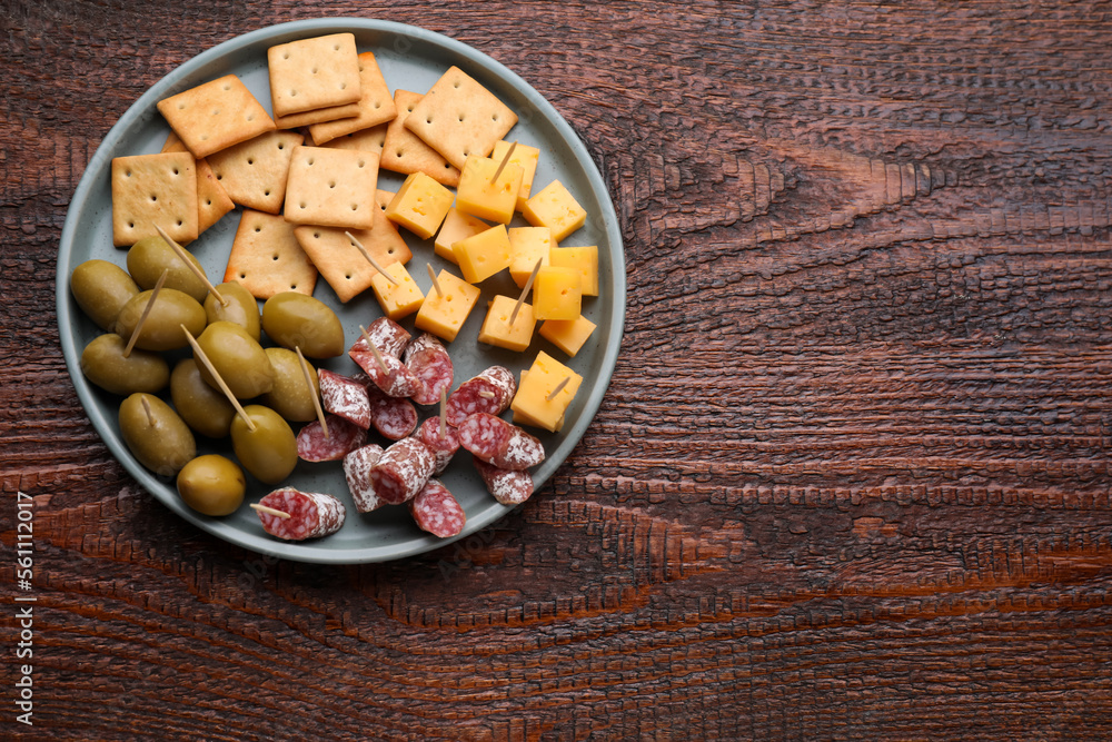 Toothpick appetizers. Pieces of cheese, sausage and olives on wooden table, top view with space for text