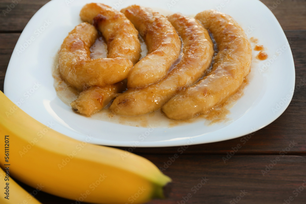 Delicious fried and fresh bananas on wooden table, closeup