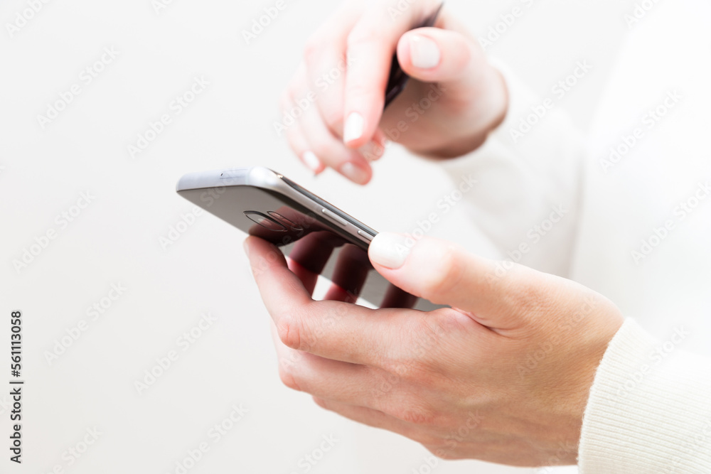 Close up of female hands holding credit card and using smartphone on white background. Woman paying securely online, using banking service, ordering in internet store. Online shopping. Close up of female hands holding credit card and using smartphone on white background. Woman paying securely online, using banking service, ordering in internet store. Online shopping.
