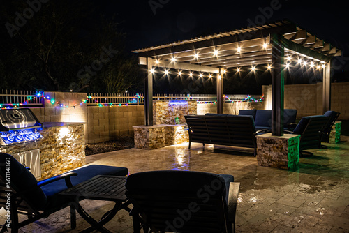 Fotografiet A resort style backyard at night with a waterfall, pergola, and a firepit at night