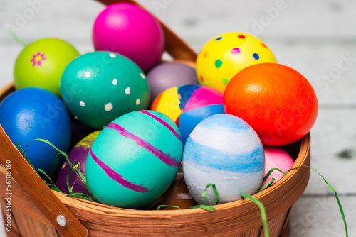 Basket with painted colorful easter eggs on wooden table