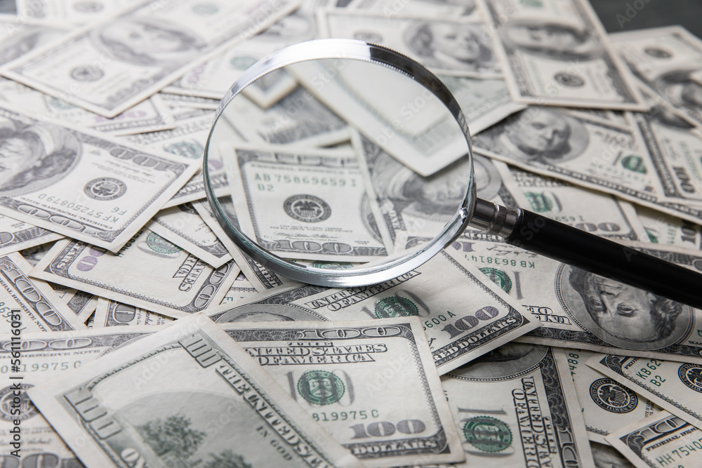 Dollar bills and a magnifying glass Dollar bills and a magnifying glass