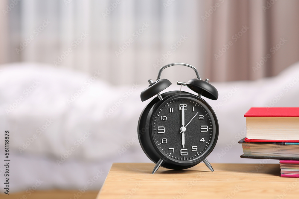 Black alarm clock and books on wooden table indoors. Space for text Black alarm clock and books on wooden table indoors. Space for text