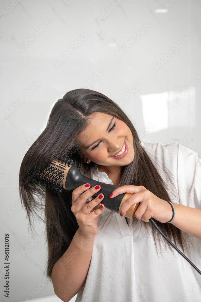 woman smiling using hair dryer brush