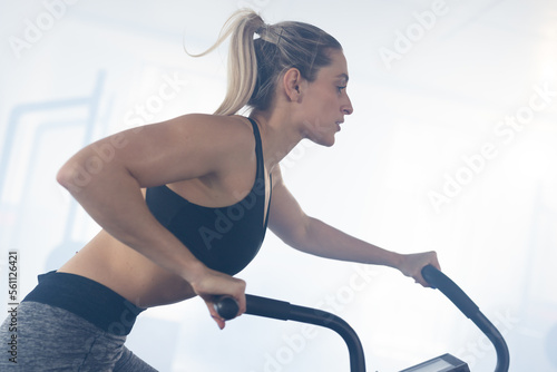 Caucasian fit woman exercising and using cross trainer at gym