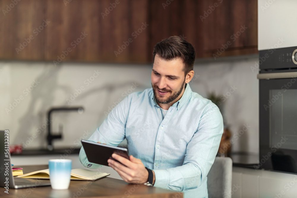 Young man using digital tablet in kitchen at home Young man using digital tablet in kitchen at home