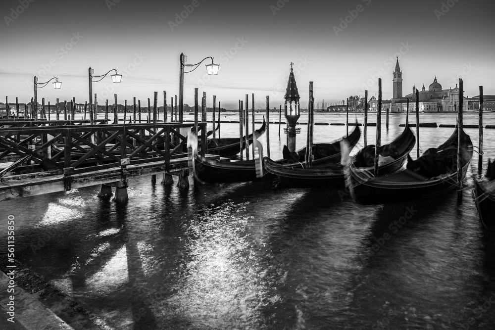 Long exposure: Gondolas floating by the shoreline of San Marco Square at sunrise in front of the Island of San Giorgio Maggiore in Venice, Italy