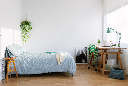 Cozy interior teenage girl room with bed, desk, laptop, photo and adolescence clothes photo