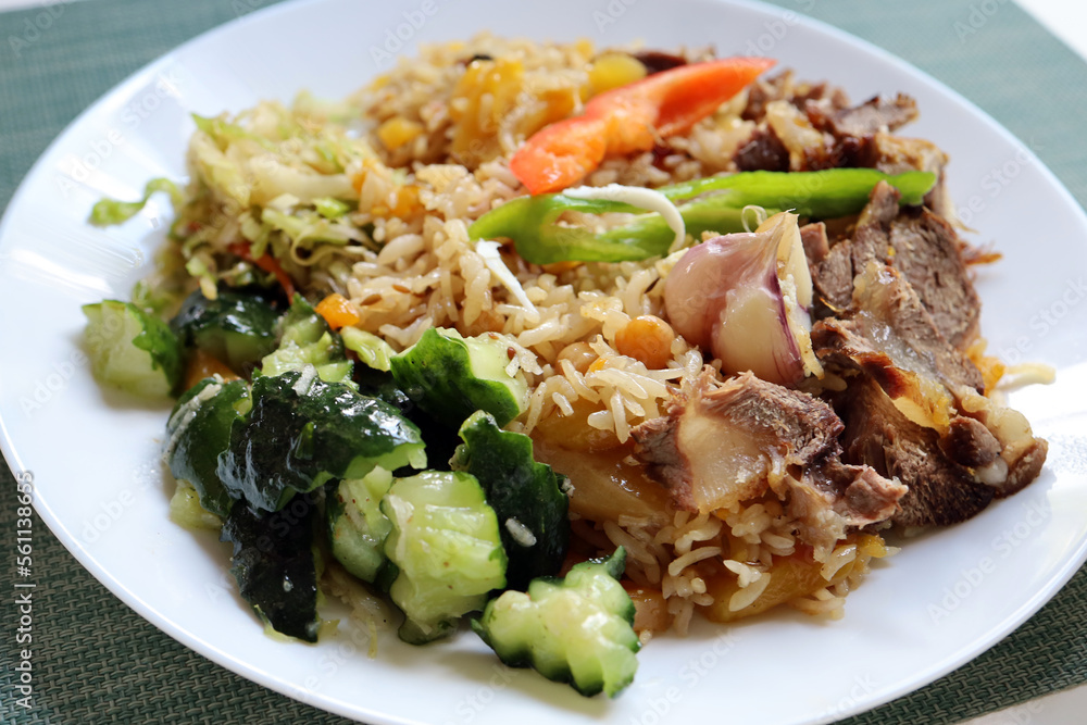 Uzbek pilaf with vegetables on the table in a cozy cafe Uzbek pilaf with vegetables on the table in a cozy cafe