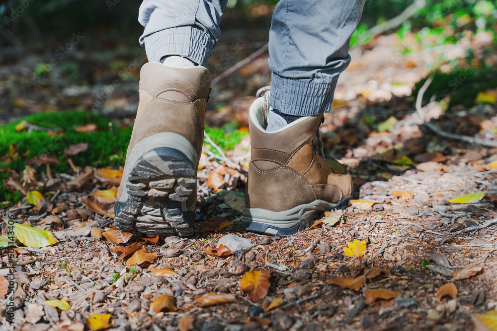 Unrecognizable male traveler or hiker walking in forest. Closeup hiking boots