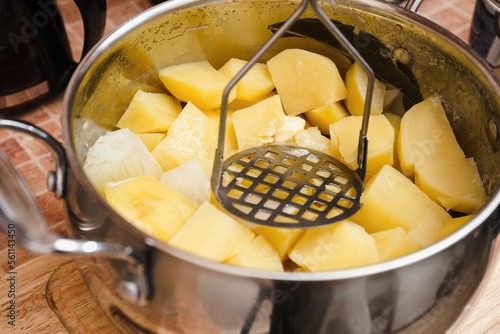 Woman preparing mashed potatoes with stainless potato masher. Cooking process, of mashed potato.