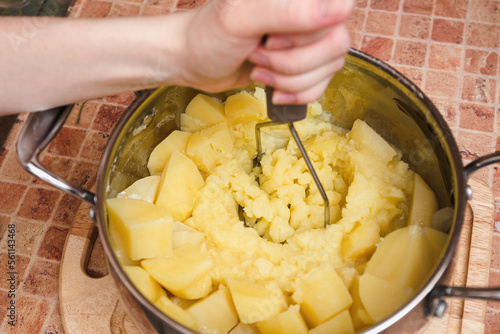 Woman preparing mashed potatoes with stainless potato masher. Cooking process, of mashed potato. photo