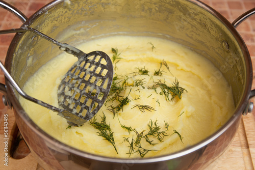 Woman preparing mashed potatoes with stainless potato masher. Cooking process, of mashed potato. photo