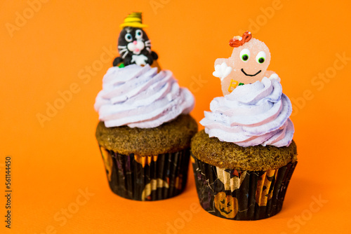 two funny halloween cupcakes with a cheshire cat and a ghost on cream photo