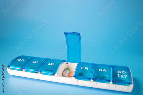 Plastic container with various pills on a blue background. Planning the use of tablets