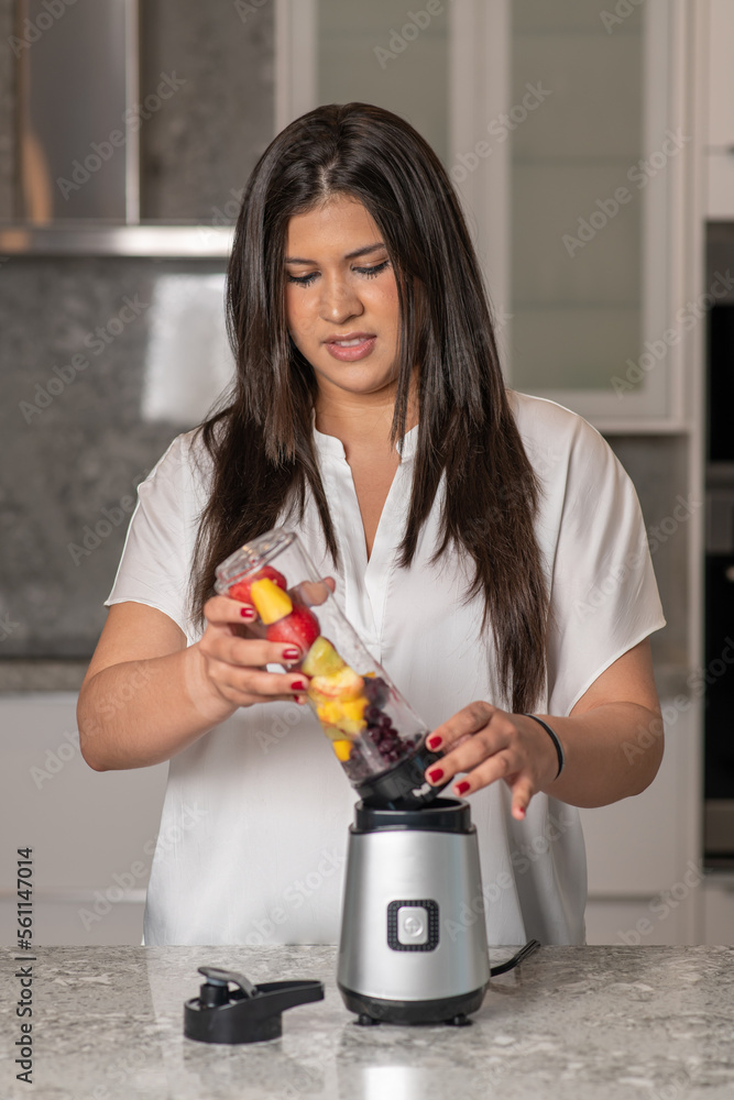 Hispanic teenager preparing a smoothie in a kitchen