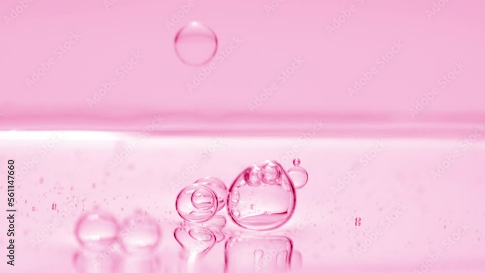 Shot of pink transparent bubbles sink to the liquid surface on pink background | Abstract skincare cosmetics with vitamin A formulation concept Shot of pink transparent bubbles sink to the liquid surface on pink background | Abstract skincare cosmetics with vitamin A formulation concept