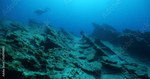 Wallpaper Mural  scuba diver exploring around a reef underwater deep blue water big rocks and bubbles ocean scenery Torontodigital.ca