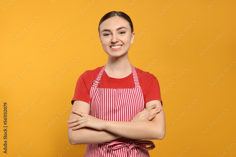 Obraz premium Beautiful young woman in clean striped apron on orange background