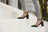 Woman in stylish black shoes walking up stairs, closeup