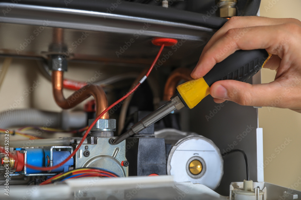 Man repairing gas boiler with screwdriver, closeup