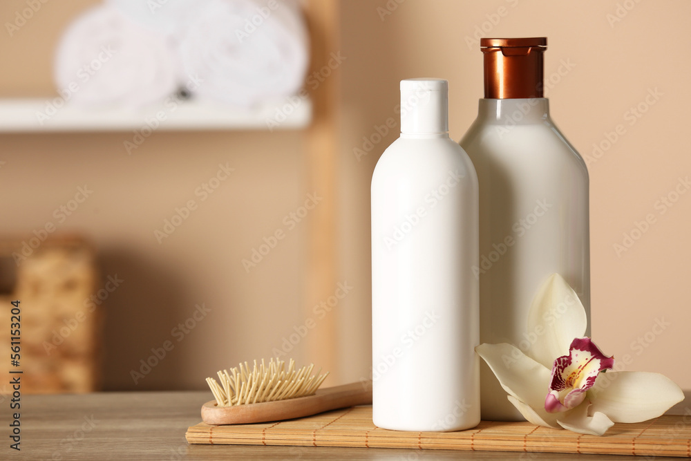 Bottles of shampoo and flower on wooden table in bathroom, space for text Bottles of shampoo and flower on wooden table in bathroom, space for text