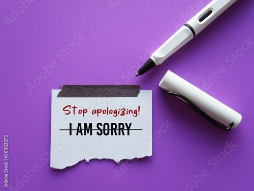 On purple background, pen writes on stick note I AM SORRY crossed off to Stop Apologizing, concept of stop being low self-respect by saying sorry too often every little thing that goes wrong photo