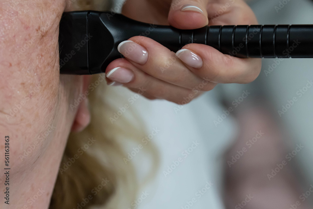 Fototapeta premium Elderly woman receiving radiofrequency lifting procedure for face skin rejuvenation and anti-age at aesthetic cosmetology center. RF lifting in beauty clinic.