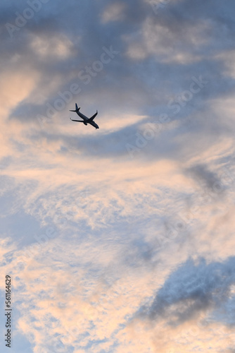 Silueta de avion volando con el cielo al atardecer con nubes coloridas