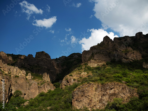 Beautiful landscape, steep slope, rocky ridge in the gorge, blue sky with fluffy clouds, wallpaper