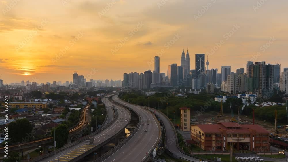 High angle aerial sunset view time lapse overlooking busy expressway and streets against a city skyline and an urban village at dusk in Kuala Lumpur, Malaysia. Zoom in motion timelapse. High angle aerial sunset view time lapse overlooking busy expressway and streets against a city skyline and an urban village at dusk in Kuala Lumpur, Malaysia. Zoom in motion timelapse.