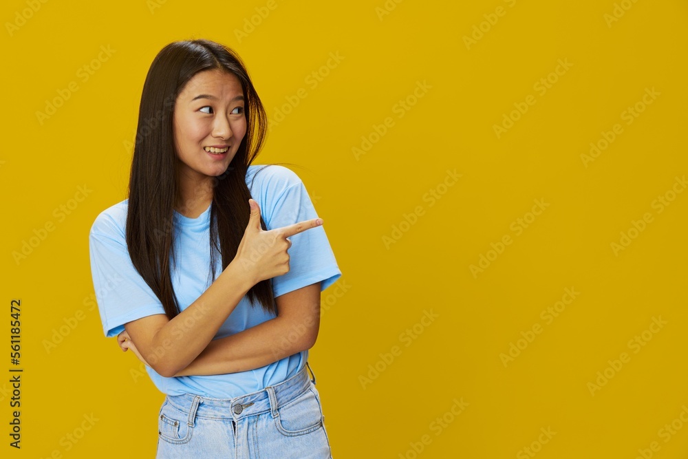 Fototapeta premium Asian woman smile with teeth hand gestures, signs and symbols on yellow background in blue t-shirt and jeans