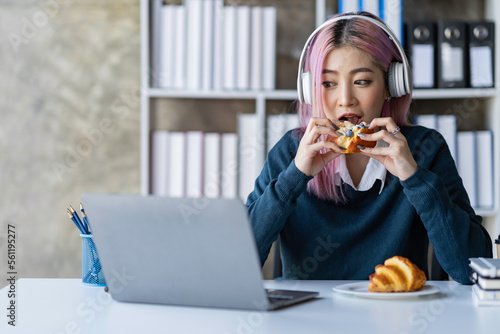Asian businesswoman sitting and eating bread watching cell phones and reading break books Relax in the office to work happily and deliciously.