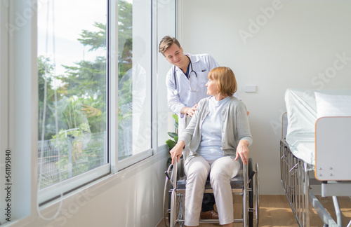 Portrait of caucasian doctor check up body of disabled old senior elderly patient using wheelchair try to walk in hospital in medical and healthcare treatment at nursing home. People lifestyle