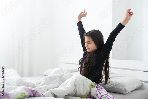 people, bedtime and rest concept - happy smiling teenage girl stretching in bed at home in morning