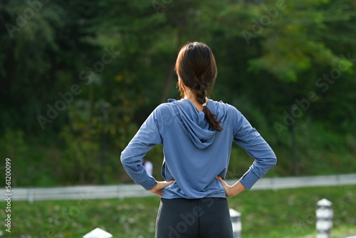 Rear view of female runner resting after sports training outdoors. Fitness, sport and healthy lifestyle concept