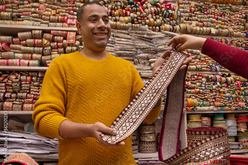 Mele fabric vendor showing border and lace to a female buyer photo