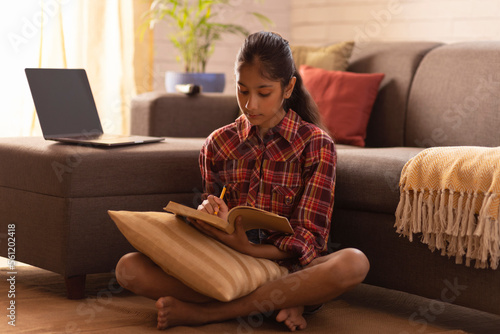 Portrait of a tween girl studying in living room at home photo