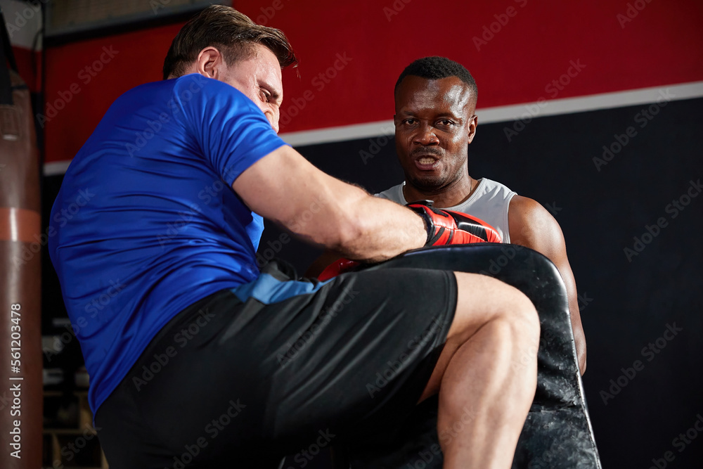 sportsman or fighter training and kickboxing with trainer in the gym sportsman or fighter training and kickboxing with trainer in the gym