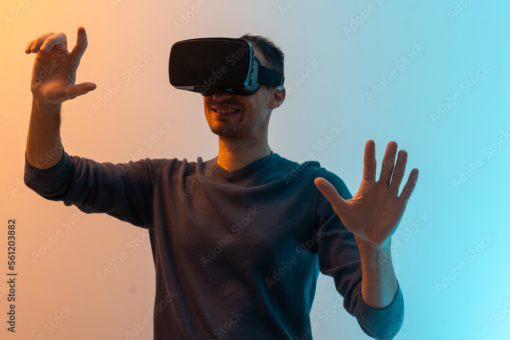 Amazing technology, online game, entertainment, study and virtual world in 3D simulation. Serious millennial man in vr glasses plays and tries to touch something, in neon, studio shot, free space. Amazing technology, online game, entertainment, study and virtual world in 3D simulation. Serious millennial man in vr glasses plays and tries to touch something, in neon, studio shot, free space.