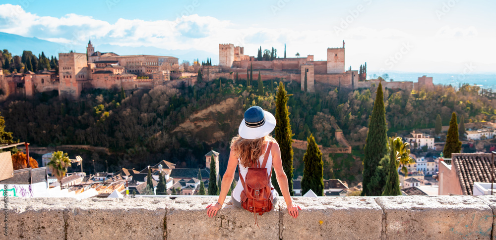 Woman tourist looking at Ancient arabic fortress Alhambra- Granada in Spain - obrazy, fototapety, plakaty 