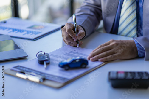 Fotografia A car dealer or sales manager offers to sell a car and explains the terms of signing a car and insurance contract